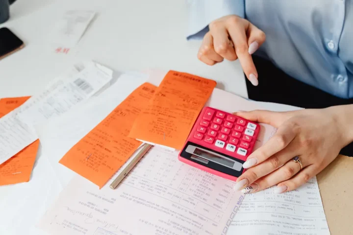 person using calculator with receipts and expense papers