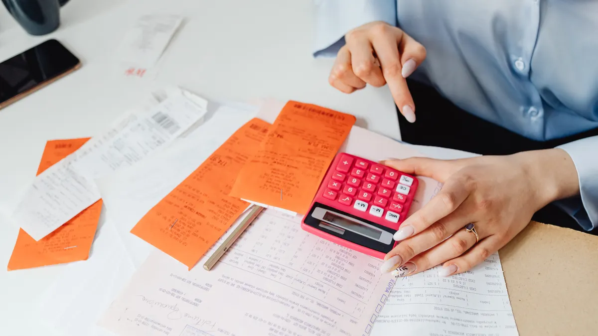 person using calculator with receipts and expense papers