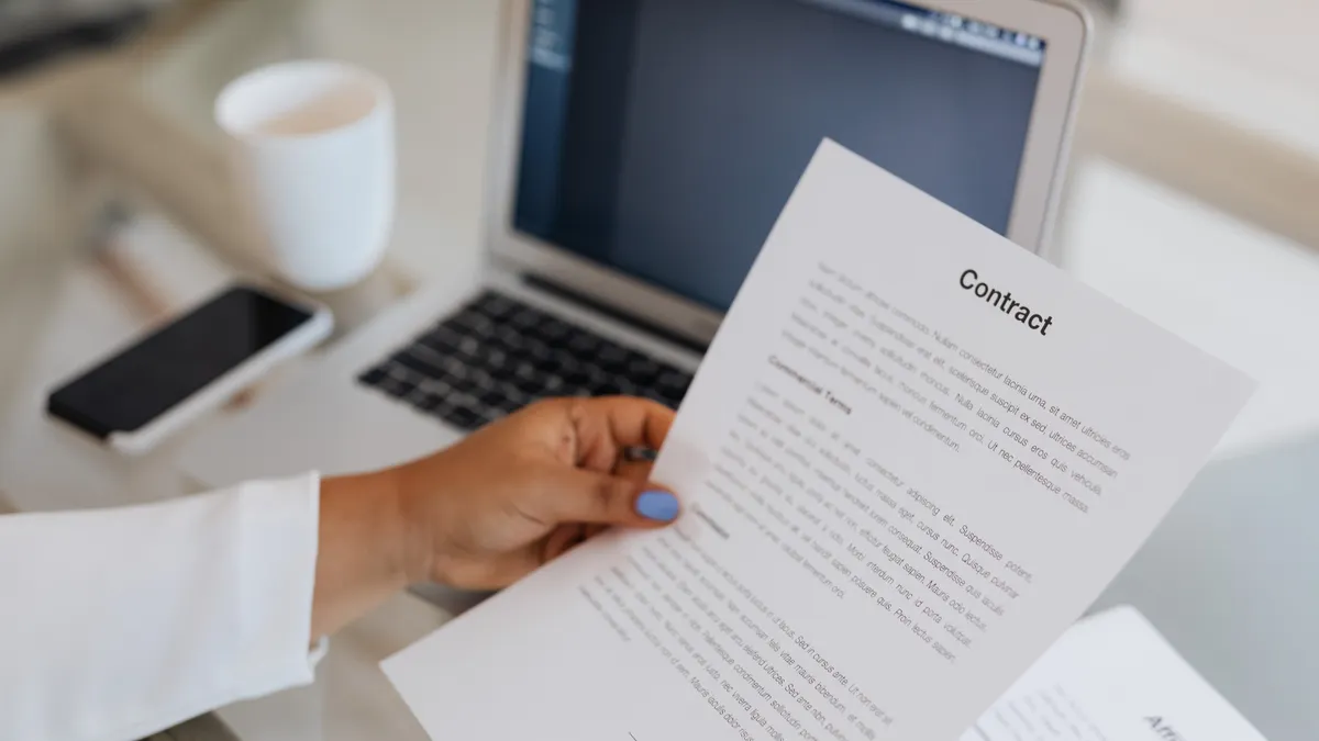 Person holding a contract document at a desk