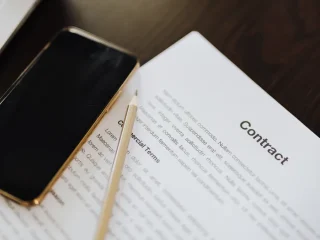 Contract paper beside laptop and phone