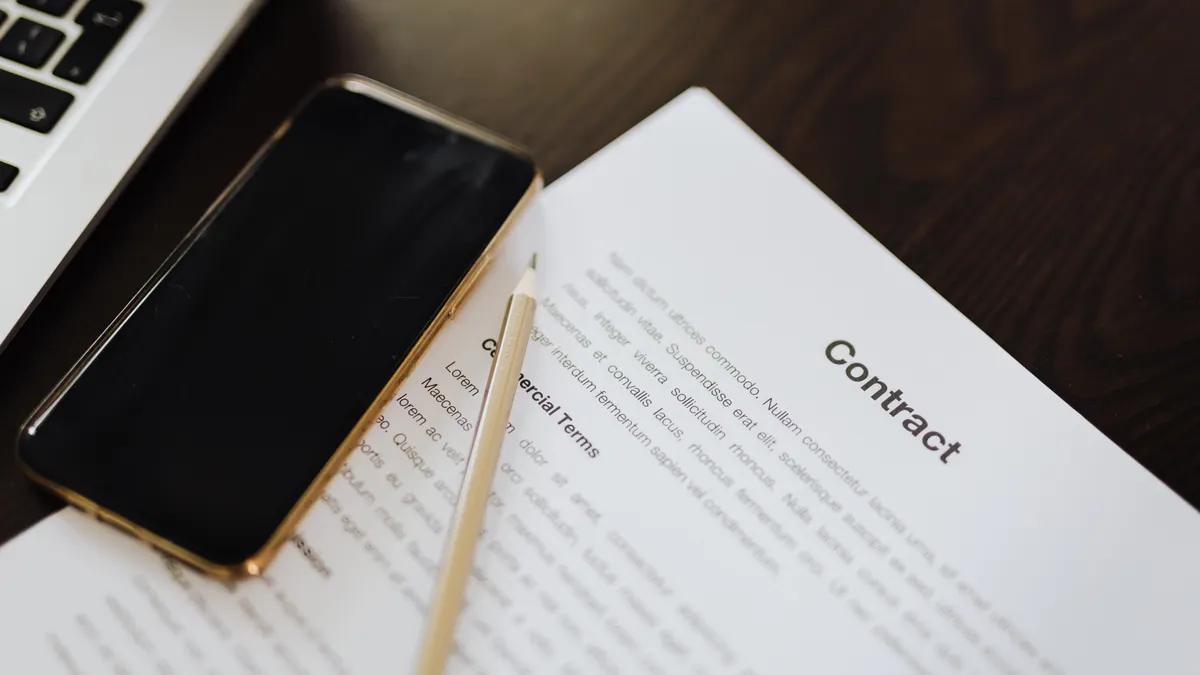 Contract paper beside laptop and phone