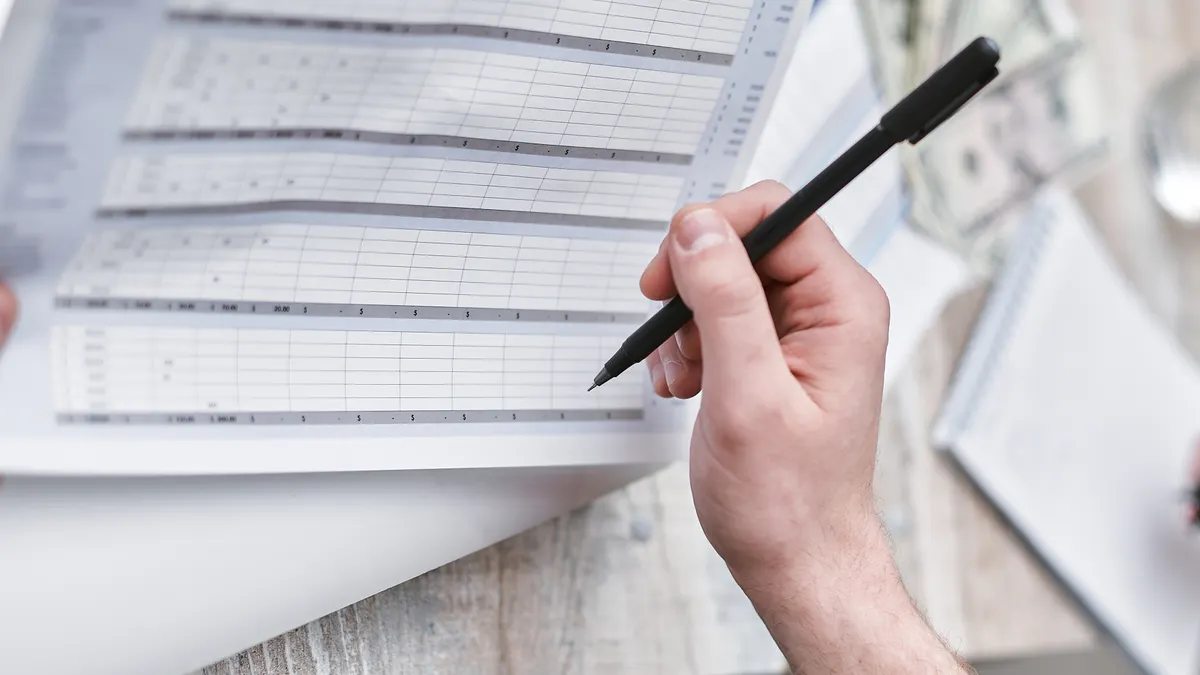 How to build a SaaS inventory from scratch hand holding a pen over a spreadsheet