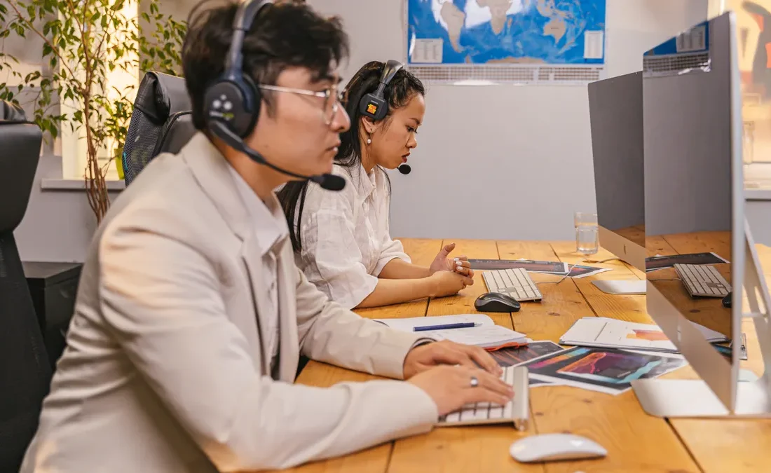 two support agents in headsets working at desktop computers