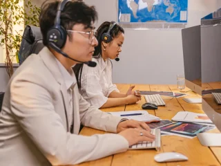 two support agents in headsets working at desktop computers