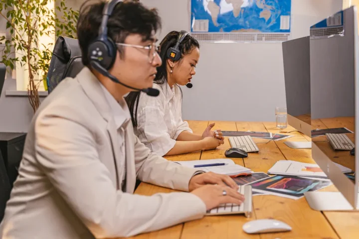 two support agents in headsets working at desktop computers