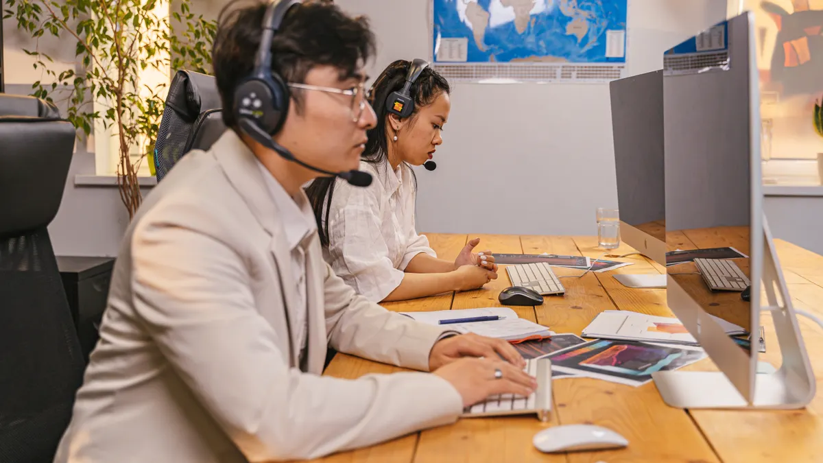 two support agents in headsets working at desktop computers