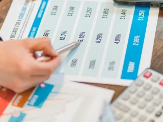 hand using a pen on a printed pricing comparison table
