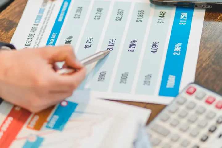 hand using a pen on a printed pricing comparison table