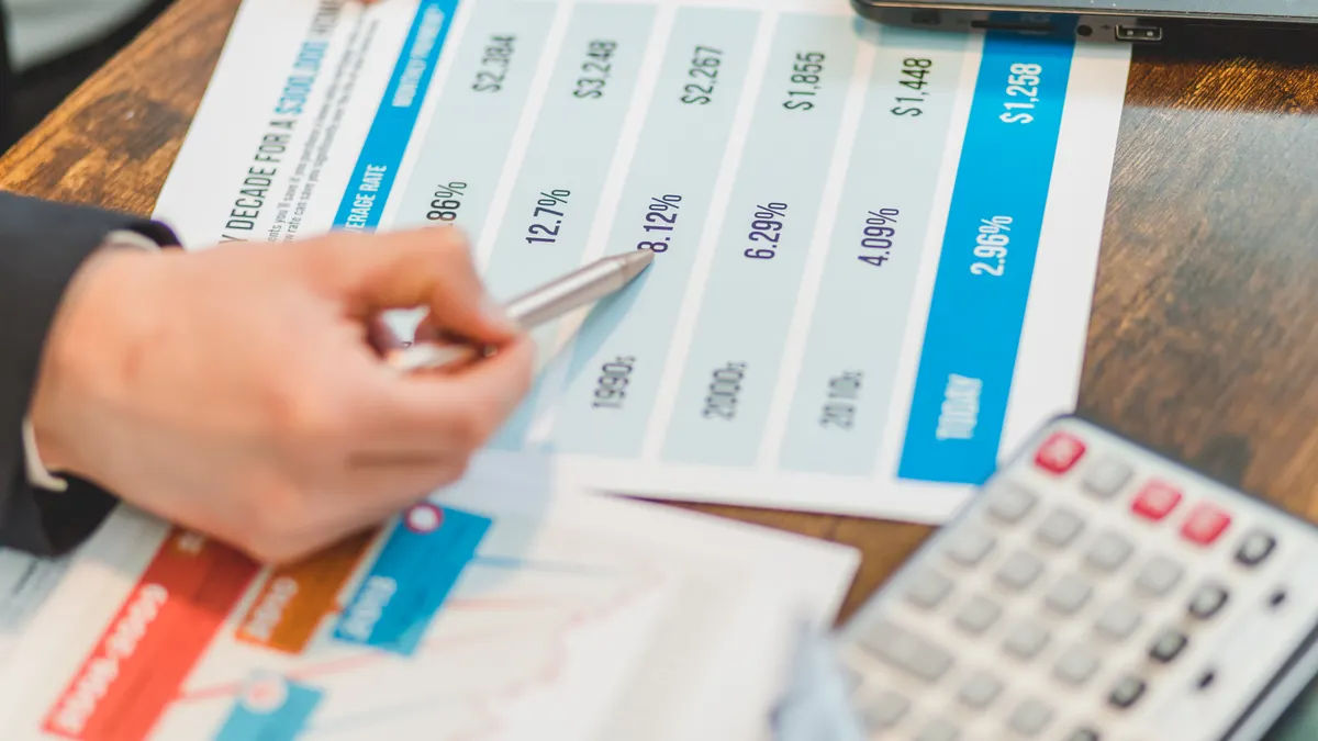 hand using a pen on a printed pricing comparison table