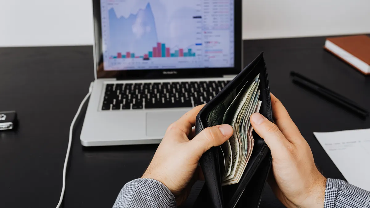 SaaS cost control and usage — The Complete Guide Hands holding an open wallet beside a laptop